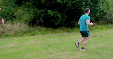 Two men running on grassy trail in scenic park