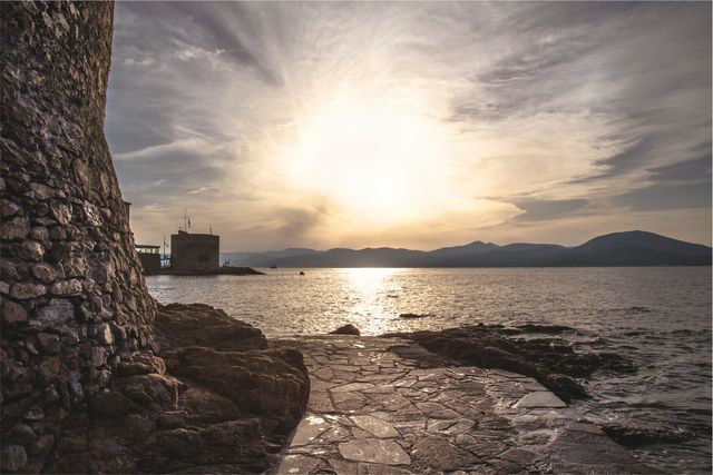 Sunset scene with medieval fortress by the calm sea, creating a peaceful and serene atmosphere. Ideal for use in travel brochures, historical documentaries, or relaxation apps.