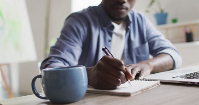 Focused Man Taking Notes in Notebook with Coffee and Laptop - Download Free Stock Images Pikwizard.com