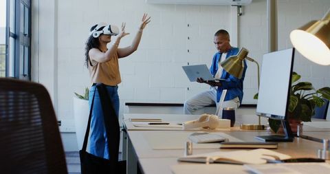 African American colleagues collaborating with VR headset and laptop in sunlit office