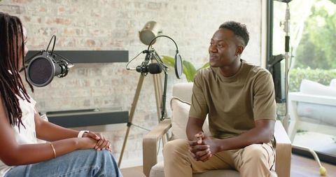 African American host and guest recording relaxed podcast interview in sunlit living room