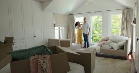 Couple Embracing in New Home Amid Moving Boxes and Furniture