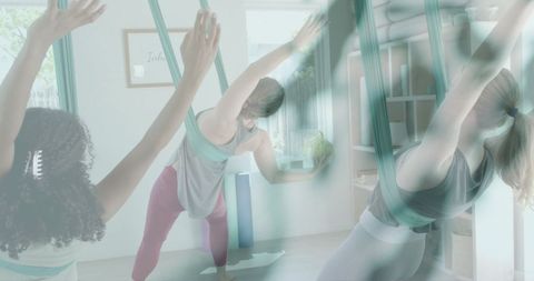 Diverse Women Practicing Aerial Yoga Surrounded by Green Leaves