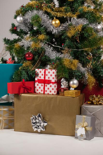 Christmas tree adorned with tinsel and ornaments, surrounded by various wrapped presents. Ideal for holiday greeting cards, festive advertisements, and seasonal promotions. Perfect for illustrating Christmas celebrations and gift-giving traditions.