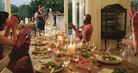 Happy couple dancing amid applauding guests at outdoor wedding reception