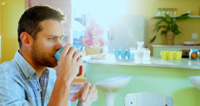 Young Man Drinking Coffee in Bright Cafeteria - Download Free Stock Images Pikwizard.com