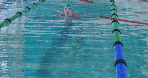 Determined Swimmer Gliding Through Lap Pool in Green Swim Cap