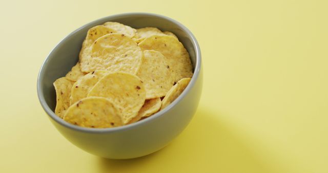 Close up of chips in a bowl with copy space on yellow surface. food and snack concept