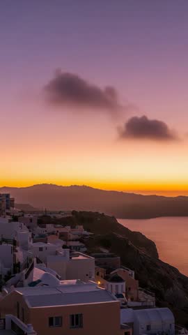 Vertical Sunset Over Coastal Cliffside Village Capturing Golden Twilight and Glowing Homes