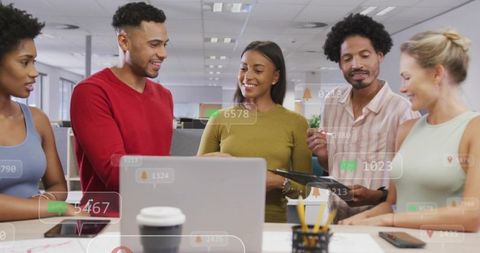Team collaborating around laptop with tablet and notification overlays in office