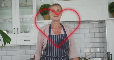Senior woman in striped apron kitchen setting with heart overlay