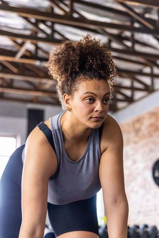 Determined african american woman training with dumbbells in industrial gym studio