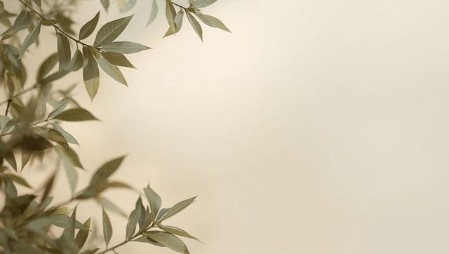 Framing green-gray eucalyptus leaves on warm beige backdrop with minimalist open space