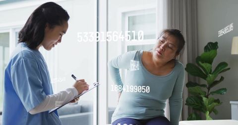 Nurse conducting home assessment while patient holding lower back in pain