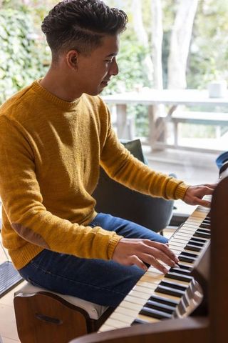 Young Man Playing Piano in Bright Home Living Room