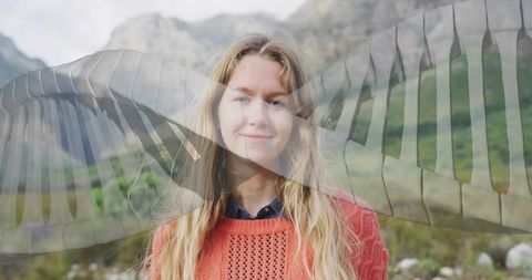 Smiling woman standing in alpine meadow wearing orange sweater with ethereal wing overlay
