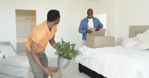Father and son organizing new home together box and bed interior