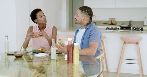 Couple Enjoying Homemade Burgers at Glass Table in Modern Kitchen