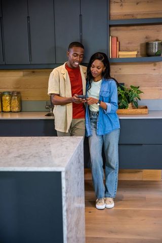 Young Couple Checking Smartphone in Modern Kitchen