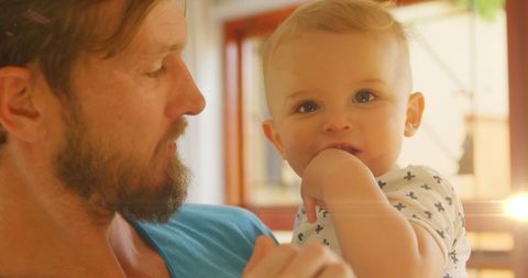 Caring Father Holding Baby Son in Bright Living Space