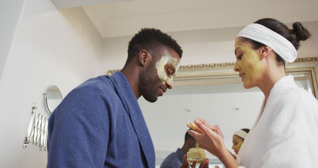 Couple applying face masks in a modern bathroom, enjoying a self-care routine together. Ideal for articles about beauty routines, self-care tips, or promoting skincare products. It can also be used in advertisements for beauty products or lifestyle blogs highlighting the importance of relaxation and bonding activities.