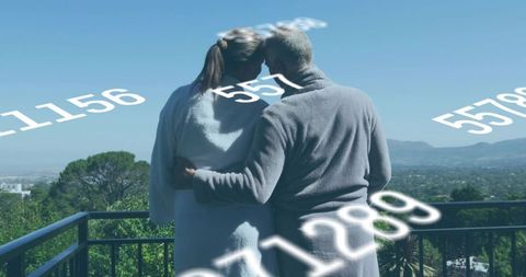 Senior couple embracing on balcony overlooking suburban valley with floating data overlay