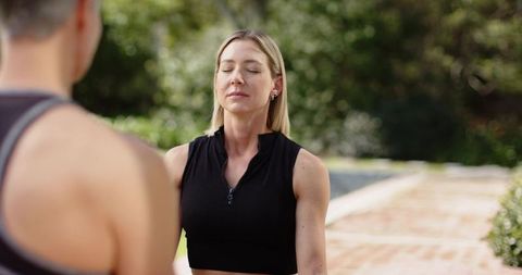 Female partners practicing guided breathwork outdoors on brick path for mindfulness and wellness