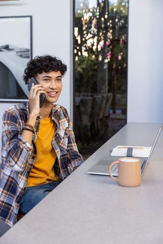 Smiling young adult using smartphone in modern workspace