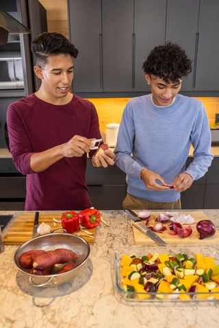 Two Friends Cooking Together, Preparing Fresh Ingredients in Modern Kitchen