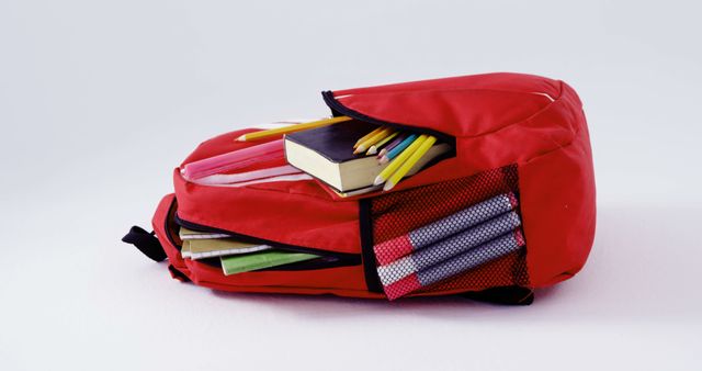 A red backpack filled with school supplies such as books and pencils, with copy space. It represents preparation for education, highlighting the importance of being equipped for learning.
