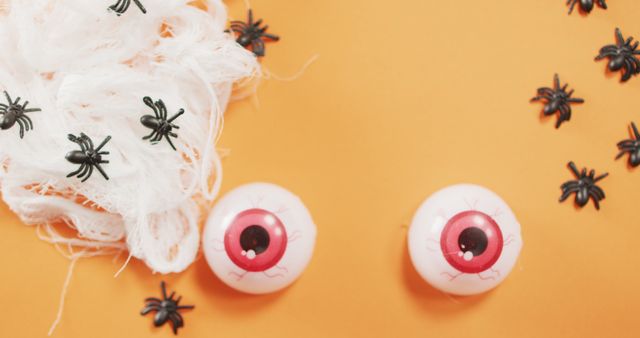 Close up view of scary eyes and spider toys against orange background. halloween festivity and celebration concept