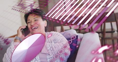 Smiling senior woman talking on smartphone at home with purple data overlays and charts