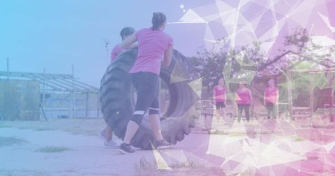 Women participating in tire flip challenge on obstacle course