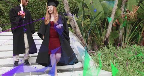Graduates descending steps wearing mortarboards and gowns, woman in red dress holding diploma