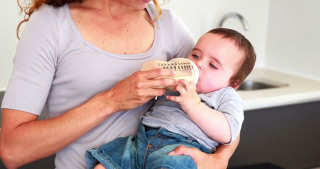 Mother Feeding Baby Bottle in Modern Kitchen - Download Free Stock Images Pikwizard.com