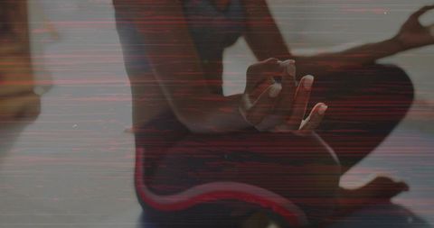 Meditating woman on blue yoga mat wearing black sports bra and red striped leggings