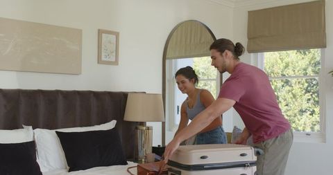 Couple Joyfully Unpacking Luggage in Cozy Bedroom