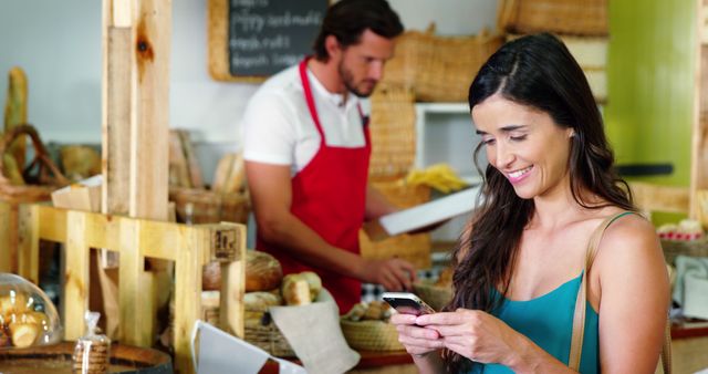 Woman Shopping in Artisan Bakery, Smiling and Using Smartphone - Download Free Stock Images Pikwizard.com
