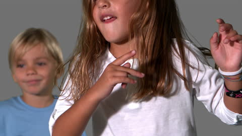 Siblings Joyfully Dancing Together Against Grey