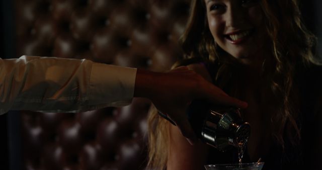 Waiter pouring cocktail in woman glass at bar counter in bar 4k