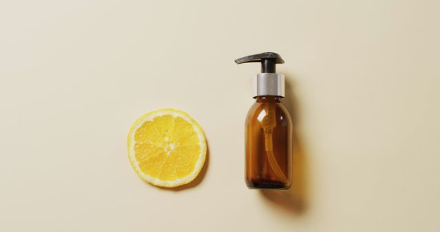 This image shows a brown bottle with a pump next to an orange slice, both placed on a beige background. Ideal for use in advertisements and marketing for skincare and beauty products, promoting natural ingredients and health-related items. Suitable for websites, social media posts, and wellness blogs.