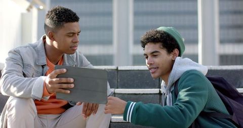 African american college students sharing tablet on campus steps collaborating outdoors urban