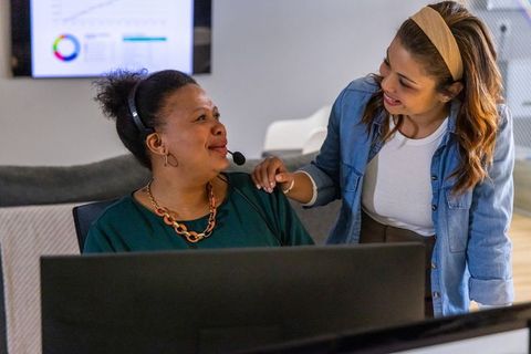 Customer service coaching with diverse teammate supporting headset operator at collaborative workspa