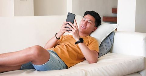 Man Relaxing on Sofa Using Smartphone in Modern Living Room