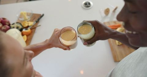 Diverse Couple Toasting with Healthy Smoothies in Modern Kitchen