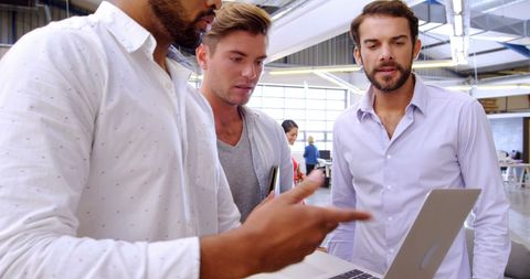 Diverse Professionals Collaborating in Modern Office on Laptop