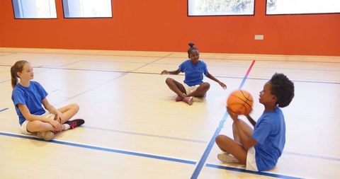 Diverse School Girls Practicing Basketball Skills Indoors