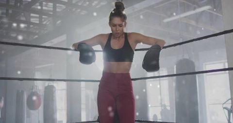 Female Boxer Resting on Rope Closing Eye During Training at Gym