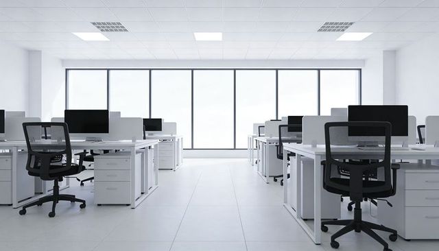Showcasing minimalist bright open-plan office with white desks and ergonomic black chairs