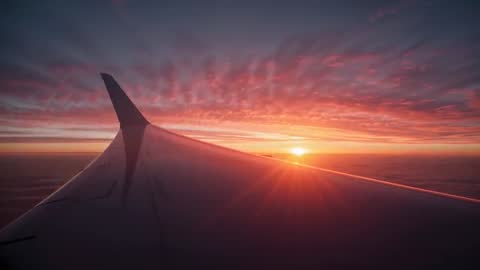 Sunrise Over Airplane Wing Elevating While Soaring Above Clouds